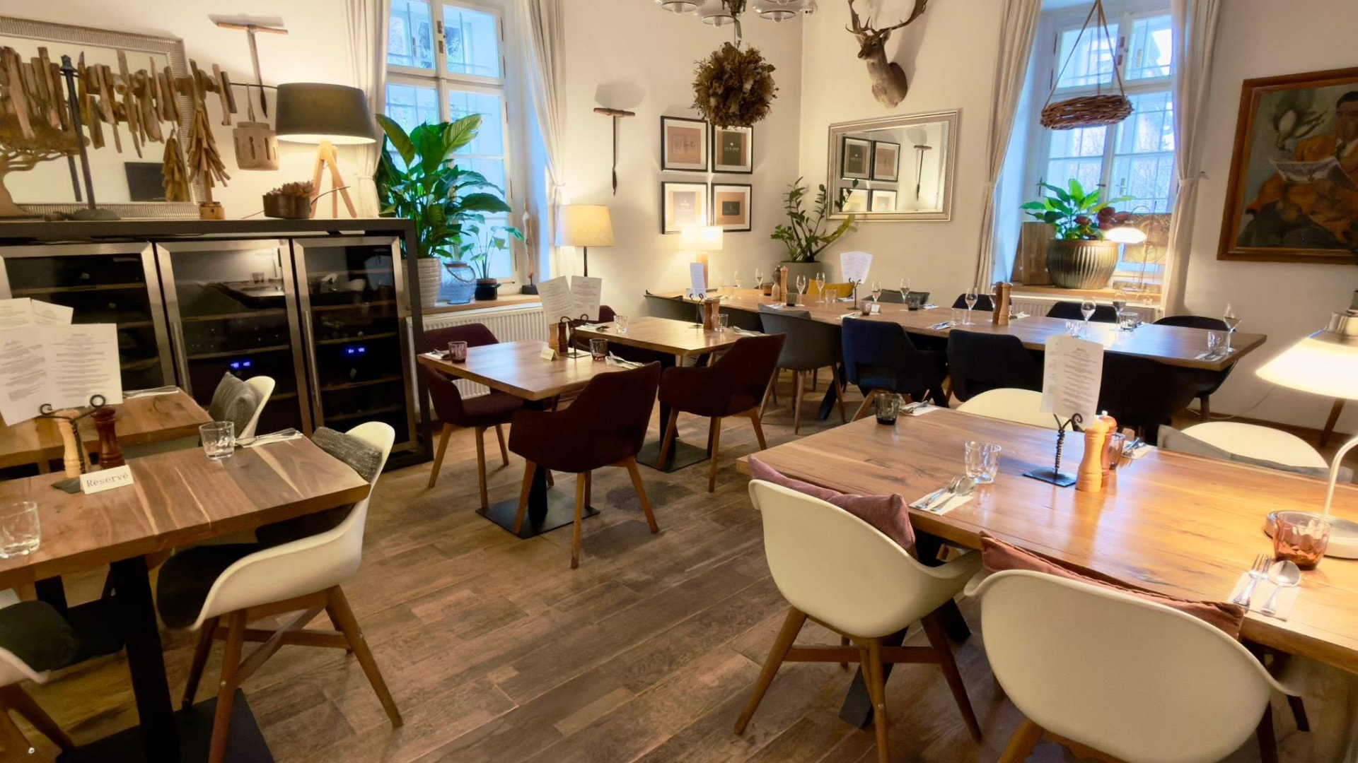 Interiér restaurace v historickém mlýně s dřevěnými stoly a vysokými okny